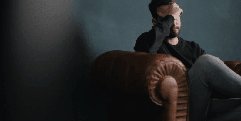 Employee Mental Health showing Man on couch with head in hand