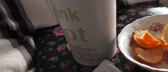 Sick leave | coffee cup, orange peels in a plate next to medicine on a bed