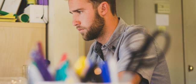 Young man looking pensive at a computer screen | misclassifying Contract Workers