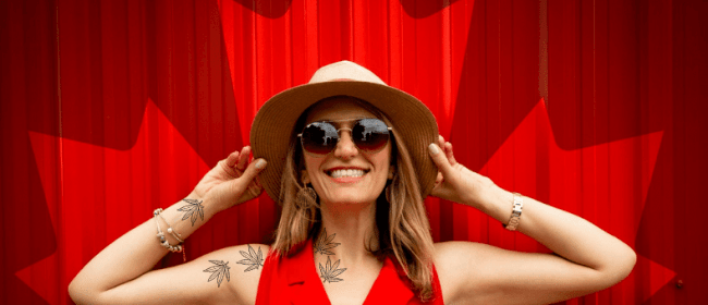 workplace law for Cannabis Users | Woman with cannabis leaf tattoos smiling in front of a curtain with the Canadian Maple Leaf